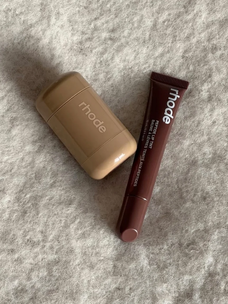 Productos de maquillaje fotografiados sobre una textura suave